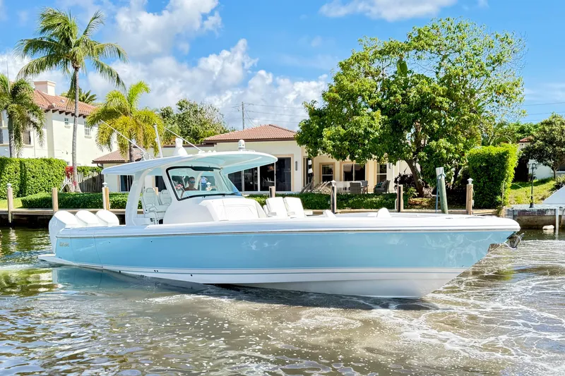 Slide: The Image of 2023 Intrepid 427 Nomad FE boat cruising near waterfront homes, under a clear blue sky. - 8