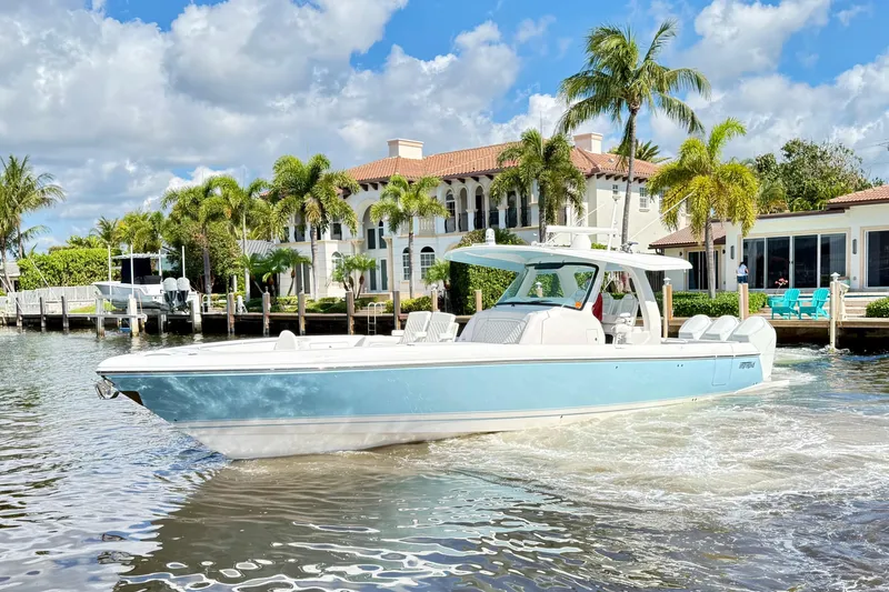 Slide: The Image of 2023 Intrepid 427 Nomad FE boat cruising near luxury waterfront homes and palm trees. - 9