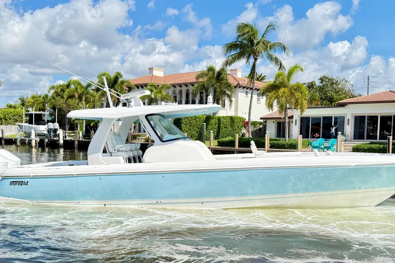 Slide: The Image of 2023 Intrepid 427 Nomad FE boat cruising near waterfront homes with palm trees. - 10