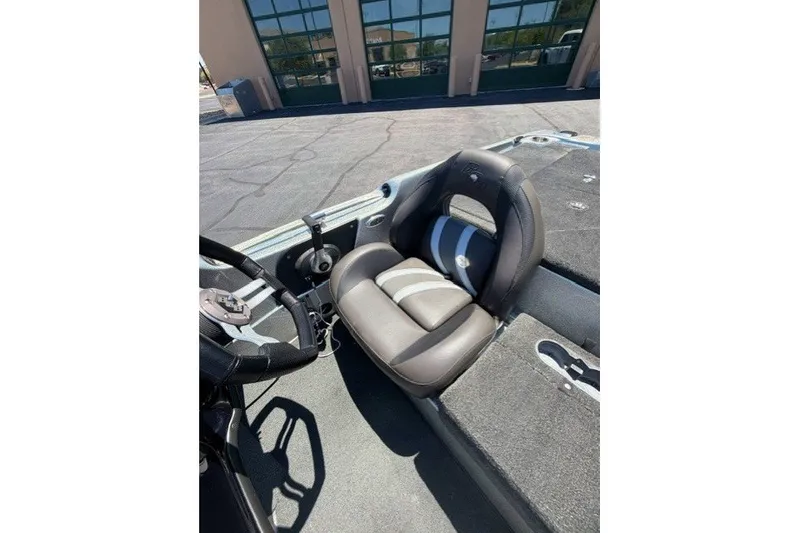 Slide: The Image of 2018 Bass Cat Caracal boat interior with steering wheel and seat, parked outdoors. - 9