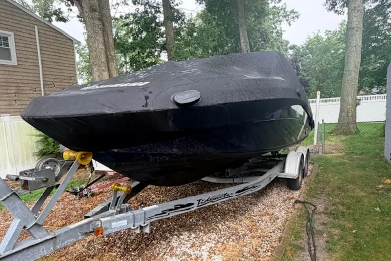 Slide: The Image of 2011 Yamaha Boats SX240 HO covered on trailer in a wooded yard. - 5