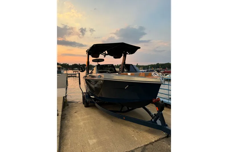 Slide: The Image of A 2022 Nautique Super Air Nautique S23 on a trailer at the dock during sunset. - 1