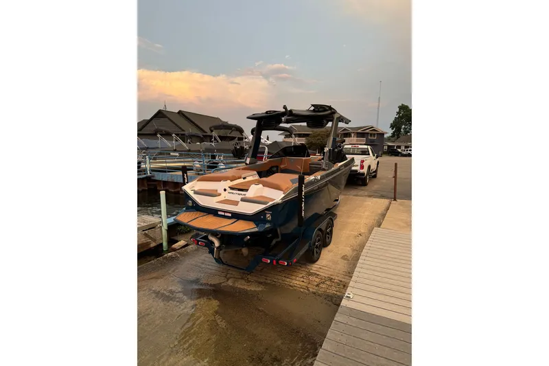 Slide: The Image of 2022 Nautique Super Air Nautique S23 boat on trailer at dock during sunset. - 2