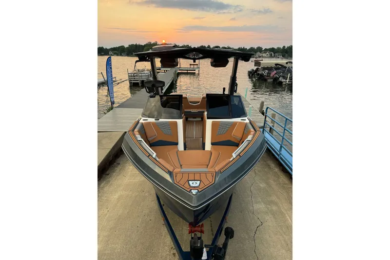 Slide: The Image of 2022 Nautique Super Air Nautique S23 boat docked at sunset, showcasing sleek design. - 3