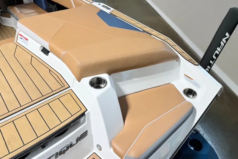Slide: The Image of 2022 Nautique Super Air Nautique S23 boat interior with tan seating and cup holders. - 12