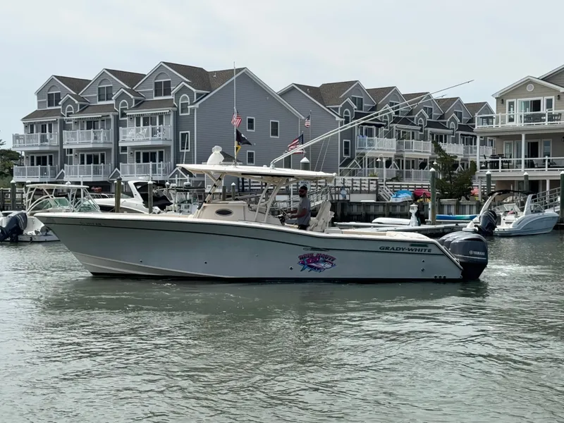 Slide: The Image of A 2016 Grady-White Canyon 336 boat cruising on calm waters in front of a row of houses. - 31