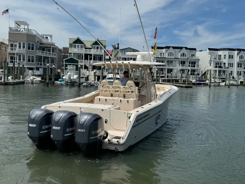 Slide: The Image of A 2016 Grady-White Canyon 336 boat with three outboard engines navigates a harbor with modern buildings in the background. - 3
