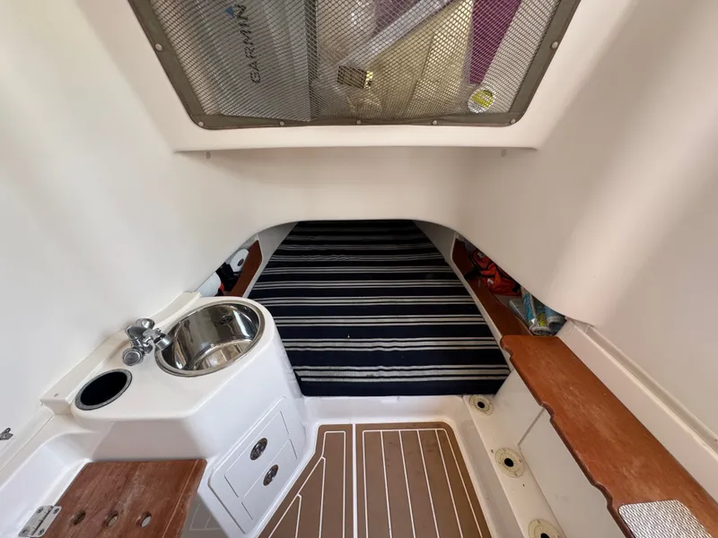 Slide: The Image of The image shows the interior of a 2016 Grady-White Canyon 336. There's a small sink, drawers, and a cushioned berth with striped fabric. - 26