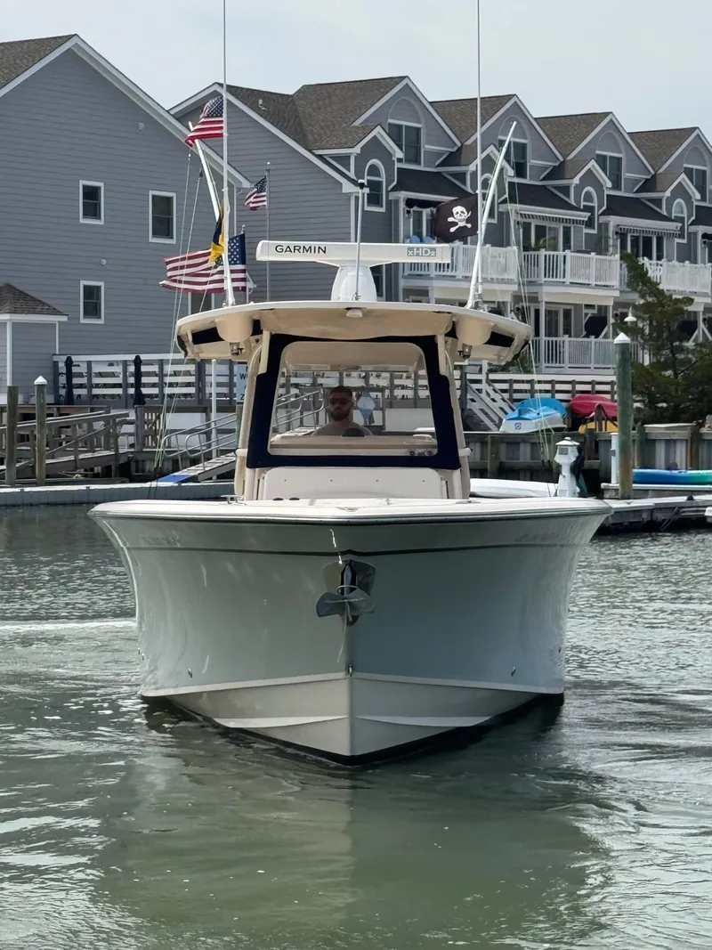 Slide: The Image of A 2016 Grady-White Canyon 336 cruising on calm waters in front of modern buildings. - 30