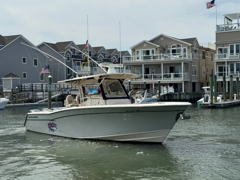 Slide: The Image of A 2016 Grady-White Canyon 336 boat navigates a harbor with modern buildings in the background. - 29