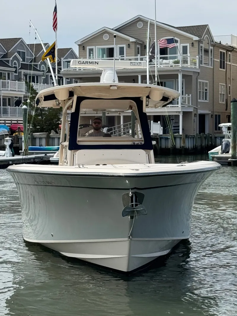 Slide: The Image of A 2016 Grady-White Canyon 336 is on the water near a dock with houses in the background. - 1