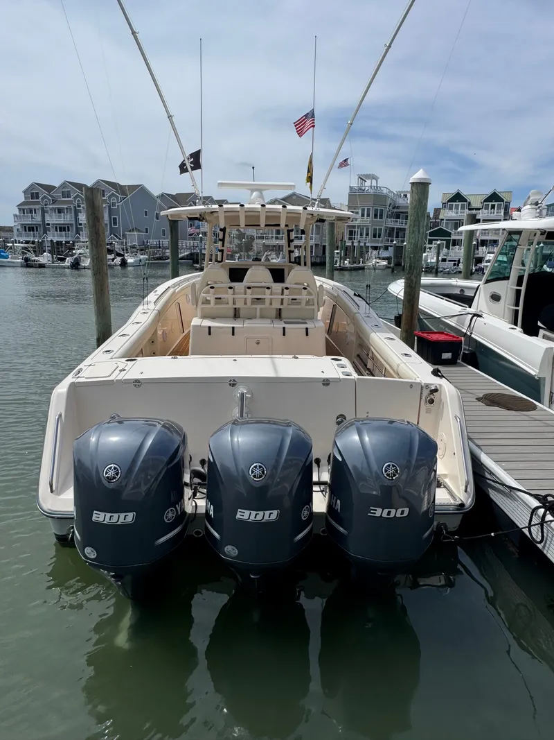 Slide: The Image of A 2016 Grady-White Canyon 336 docked in a marina. Three outboard engines are visible. - 28
