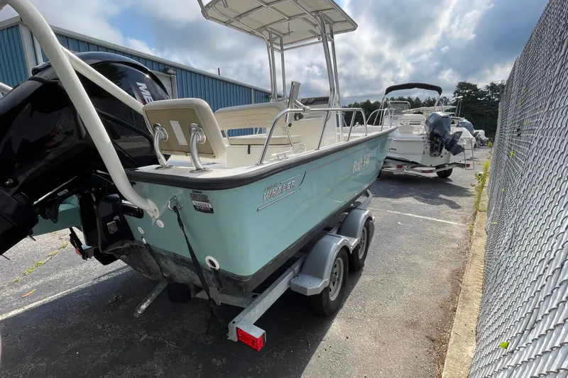 Slide: The Image of 2023 Boston Whaler 190 Montauk boat on trailer, parked outdoors near a fence. - 7
