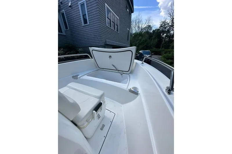 Slide: The Image of 2021 Edgewater 170CC boat with open storage compartment, parked near a house. - 11