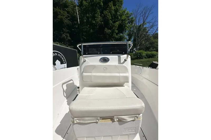 Slide: The Image of 2021 Edgewater 170CC boat interior with white seating and console, surrounded by greenery. - 13