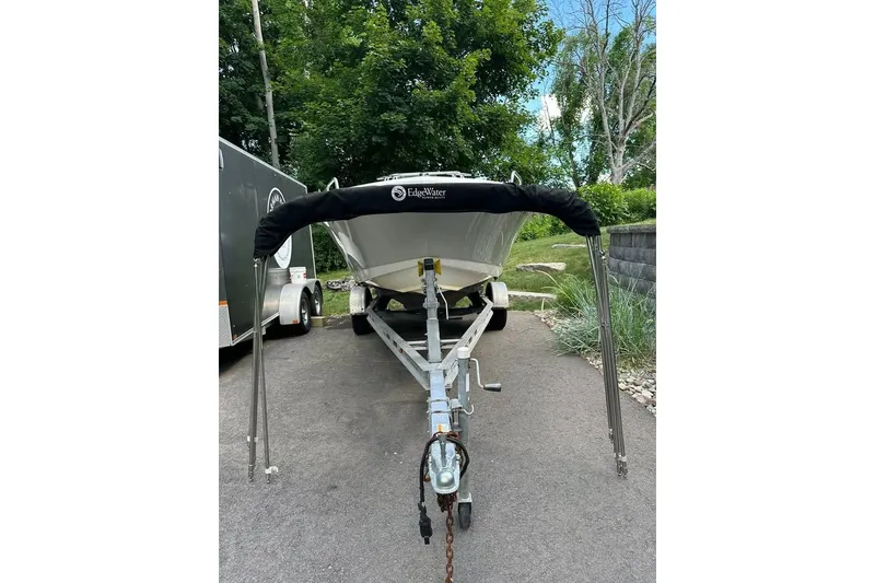 Slide: The Image of 2021 Edgewater 170CC boat on trailer, parked on a driveway with greenery. - 3