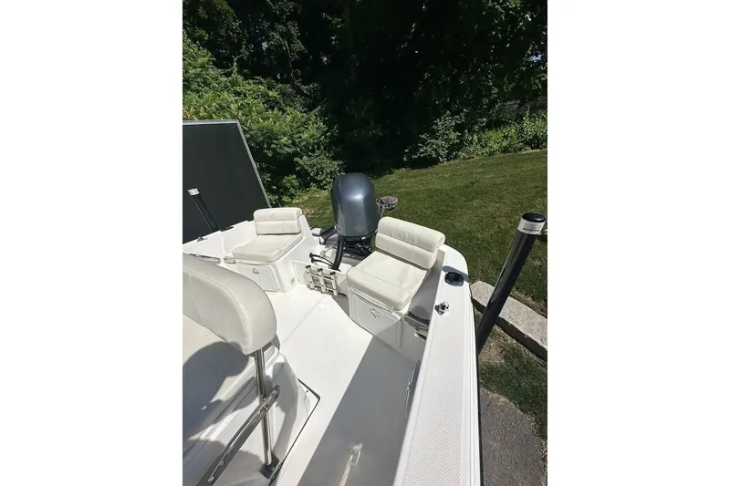 Slide: The Image of 2021 Edgewater 170CC boat interior with seating and outboard motor, surrounded by greenery. - 14