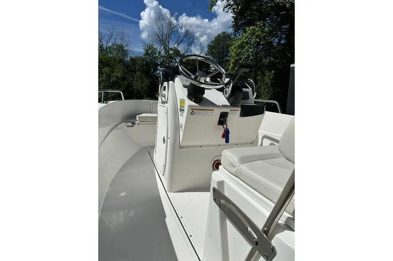 Slide: The Image of 2021 Edgewater 170CC boat interior with steering console and seating, surrounded by trees. - 5