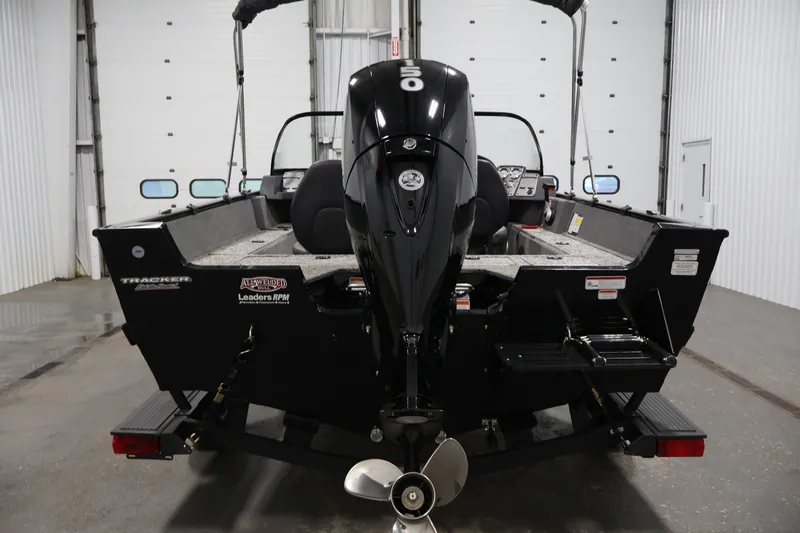 Slide: The Image of 2025 Tracker Pro Guide V-175 WT boat in a garage, rear view with motor. - 6