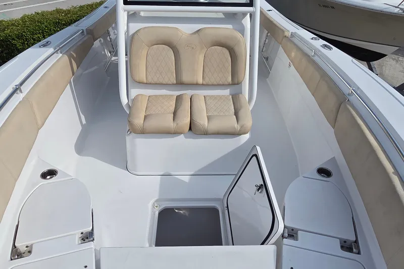 Slide: The Image of 2018 Sportsman Open 312 Center Console boat interior with beige seating and storage compartment. - 9