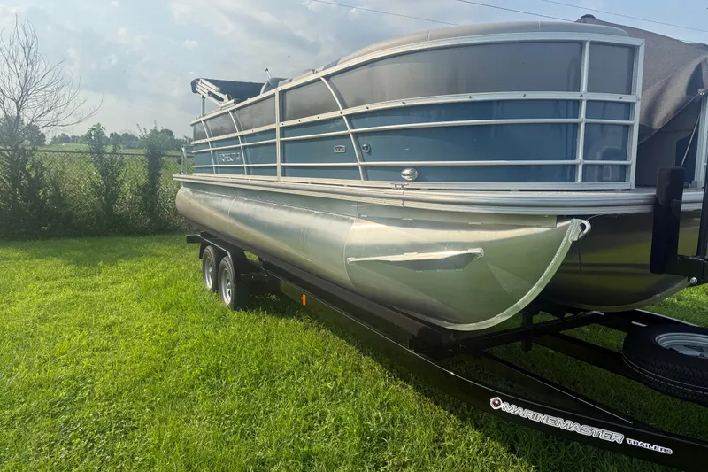 Slide: The Image of 2025 Trifecta 24 RF LE pontoon boat on trailer, parked on green grass. - 3