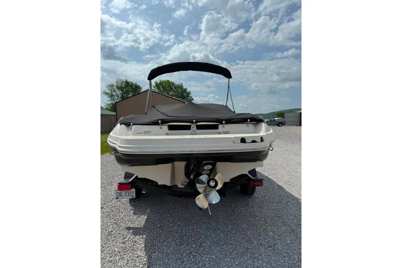 Slide: The Image of 2006 Sea Ray 220 Select boat with cover, parked on gravel under a cloudy sky. - 3