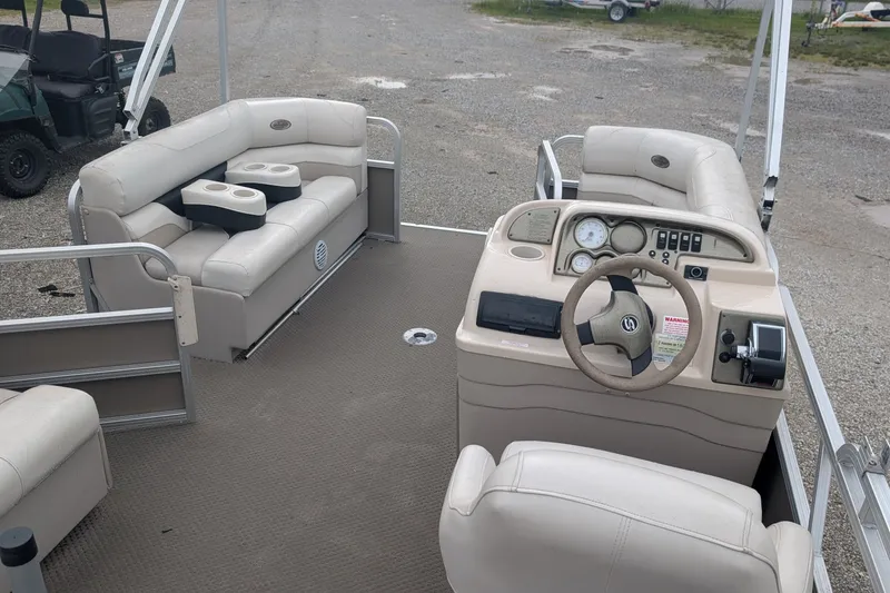 Slide: The Image of 2005 Sylvan 8520 Mirage Cruise RE pontoon boat interior with beige seating and helm controls. - 7