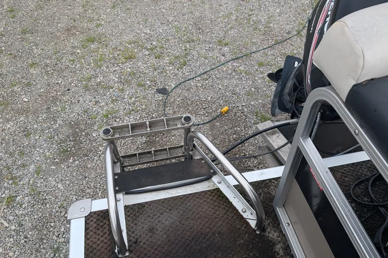 Slide: The Image of 2005 Sylvan 8520 Mirage Cruise RE boat ladder and seating area on gravel surface. - 8