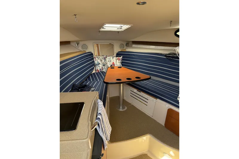 Slide: The Image of 2006 Wellcraft 290 Coastal cabin interior with striped seating and wooden table. - 9
