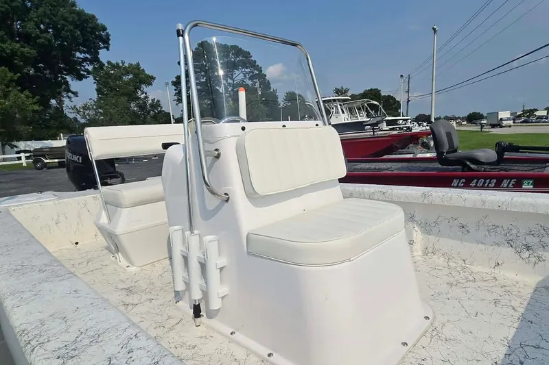 Slide: The Image of 2027 Coastal Skiff 171 boat with white seating and console, parked outdoors. - 14
