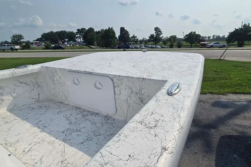 Slide: The Image of 2027 Coastal Skiff 171 boat with marbled deck, parked near a road. - 13