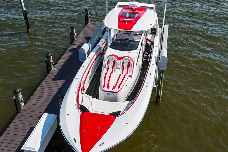 Slide: The Image of 2016 MTI V42 boat docked, featuring sleek red and white design on calm water. - 2