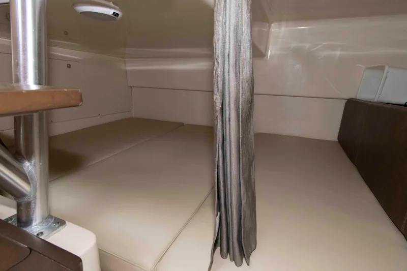 Slide: The Image of 2016 Boston Whaler 315 Conquest cabin interior with beige seating and privacy curtain. - 27
