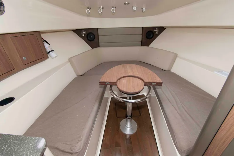 Slide: The Image of 2016 Boston Whaler 315 Conquest cabin interior with seating and wooden table. - 25
