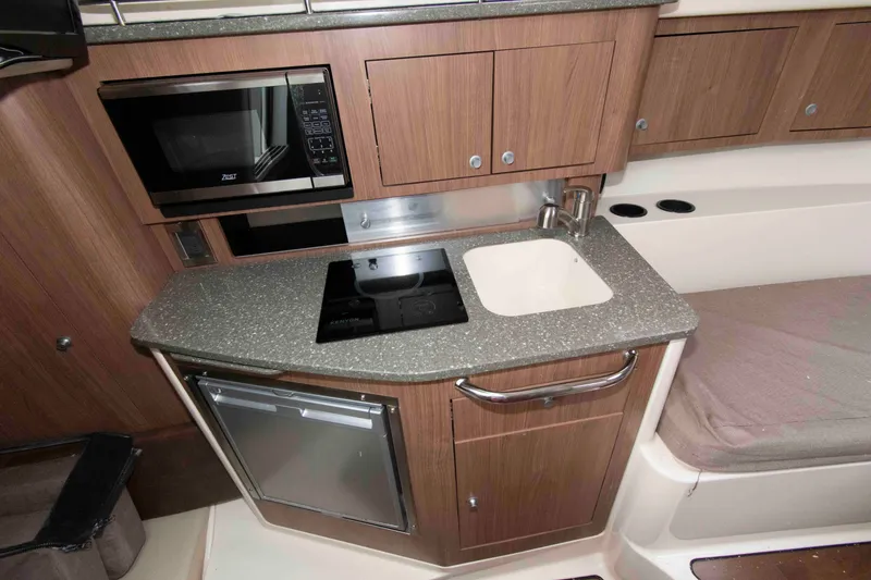 Slide: The Image of 2016 Boston Whaler 315 Conquest galley with microwave, sink, and compact fridge. - 24