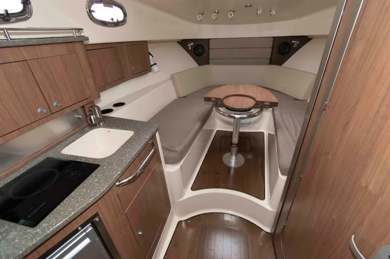 Slide: The Image of Interior of 2016 Boston Whaler 315 Conquest, featuring a cozy cabin with kitchenette and seating. - 23