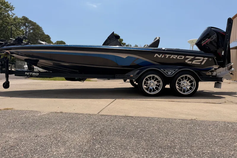 The Image of 2024 TRACKER NITRO Z21XL boat on trailer, sleek design, shiny wheels, outdoor setting. - 0