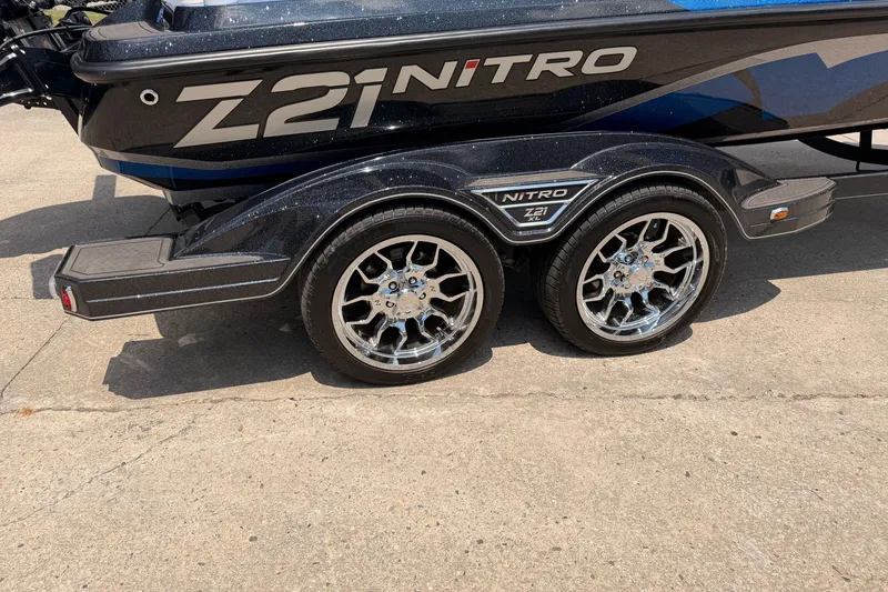 Slide: The Image of 2024 TRACKER NITRO Z21XL boat trailer with shiny chrome wheels on concrete surface. - 18
