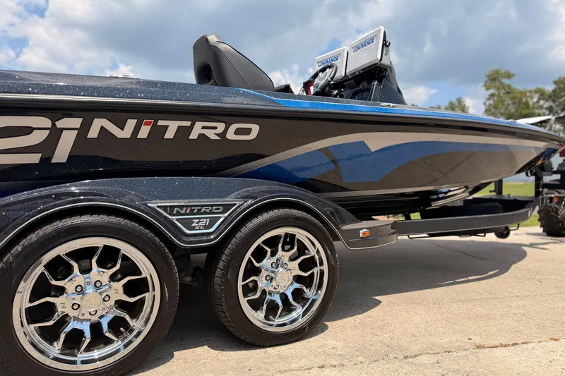 Slide: The Image of 2024 TRACKER NITRO Z21XL boat with sleek design and chrome wheels on trailer. - 2