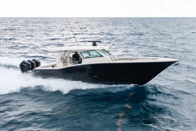 The Image of 2022 Scout 425 LXF boat cruising on open water with triple outboard engines. - 0
