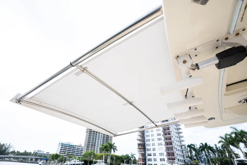 Slide: The Image of 2022 Scout 425 LXF boat with extended sunshade, cityscape in background. - 32