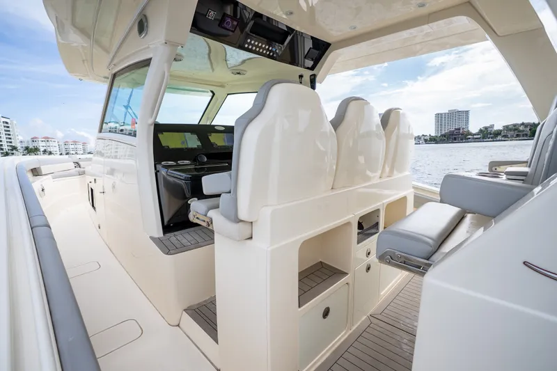 Slide: The Image of 2022 Scout 425 LXF boat interior with helm seats and storage, docked by waterfront buildings. - 25