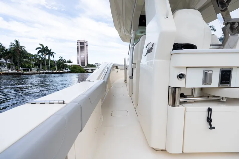 Slide: The Image of 2022 Scout 425 LXF luxury boat docked by waterfront with palm trees and high-rise building. - 13
