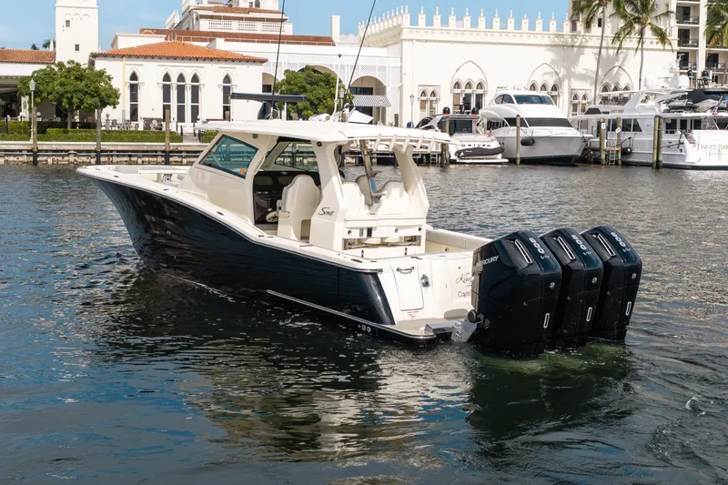 Slide: The Image of 2022 Scout 425 LXF boat with four engines docked near luxury waterfront buildings. - 6