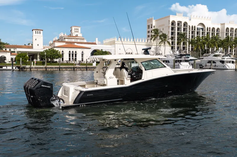 Slide: The Image of 2022 Scout 425 LXF boat cruising near luxury waterfront buildings. - 4