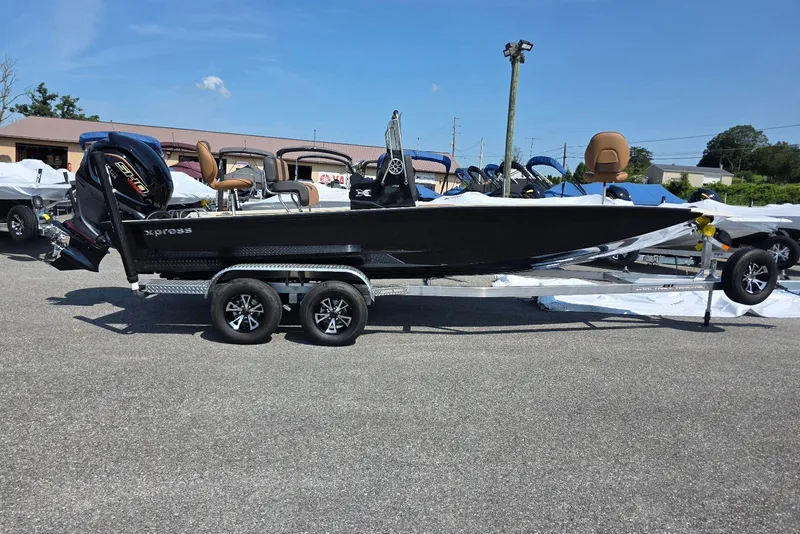 The Image of 2027 Xpress H22B Bay boat on trailer, displayed outdoors under clear sky. - 1