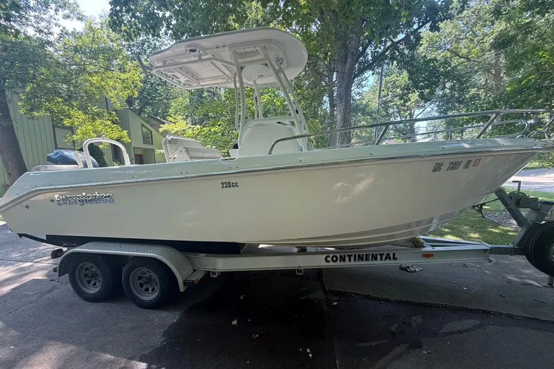Slide: The Image of 2011 Everglades 230 Center Console boat on trailer, surrounded by trees. - 2