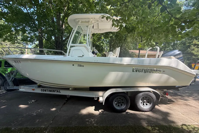 Slide: The Image of 2011 Everglades 230 Center Console boat on trailer, parked under trees. - 3