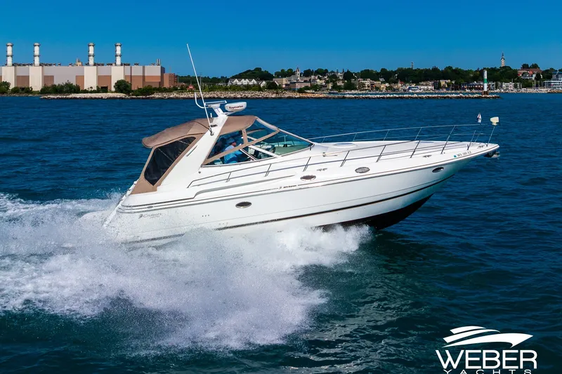 Slide: The Image of 2001 Cruisers Yachts 3870 Express cruising on blue water near industrial shoreline. - 5
