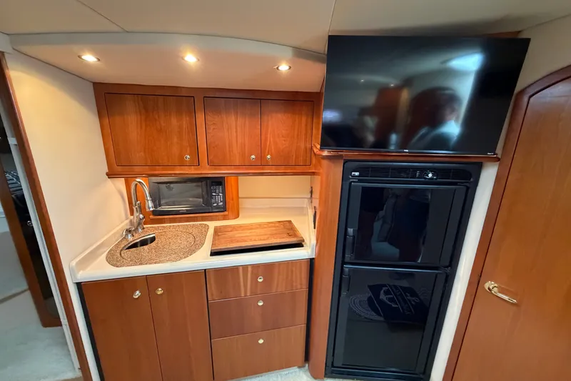 Slide: The Image of 2001 Cruisers Yachts 3870 Express interior kitchen with wood cabinets, sink, microwave, and refrigerator. - 21